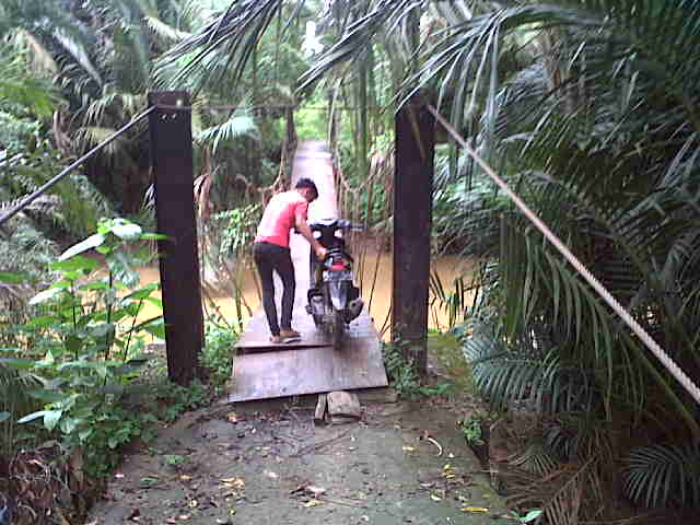 Masyarakat yang hendak keladang terpaksa turun dari kendaraannya saat melewati jembatan gantung yang rusak tergerus air Sungai