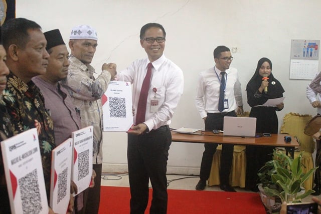 Kepala KPw BI Lhokseumawe,Yufrizalsaat menyerahkan QRIS kepada beberapa pengurus masjid di Kota Lhokseumawe, BI juga melakukan simulasi atau ujicoba beramal dengan metode non tunai, Senin di Gedung BI Lhokseumawe, (23/12).