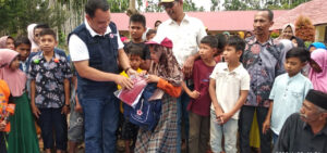 Tantawi, ketua PMI Aceh Utara secara simbolis menyerahkan pakaian sekolah kepada korban banjir
